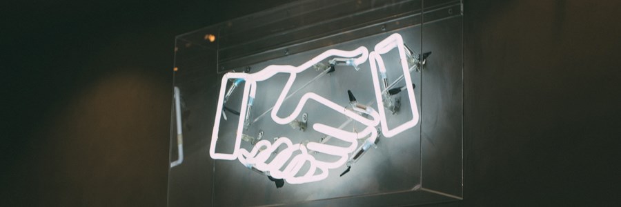 Neon sign depicting 2 hands shaking each other